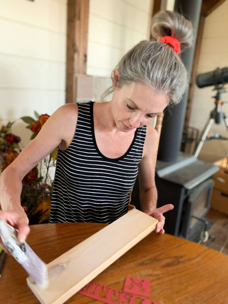 Stephanie Ray creates a distressed look with paint on scrap wood for DIY garden sign