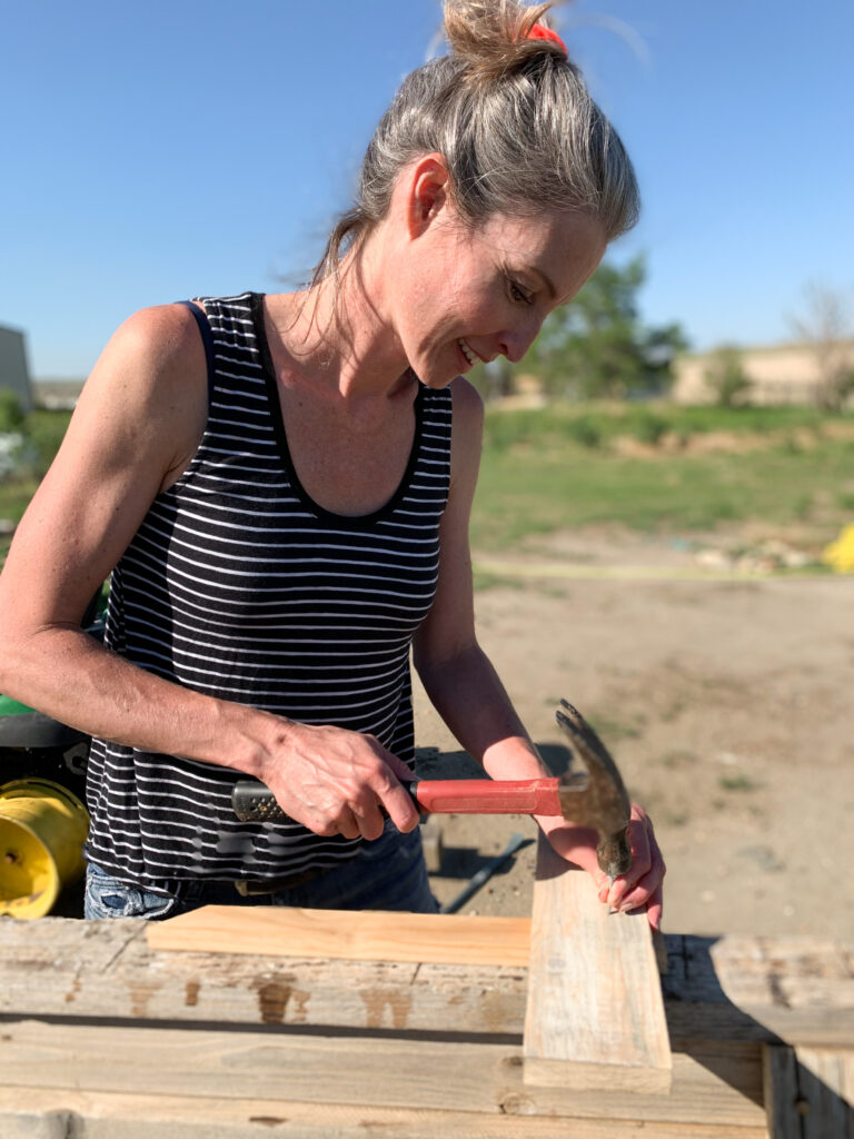 Stephanie Ray nails DIY garden sign to a stake