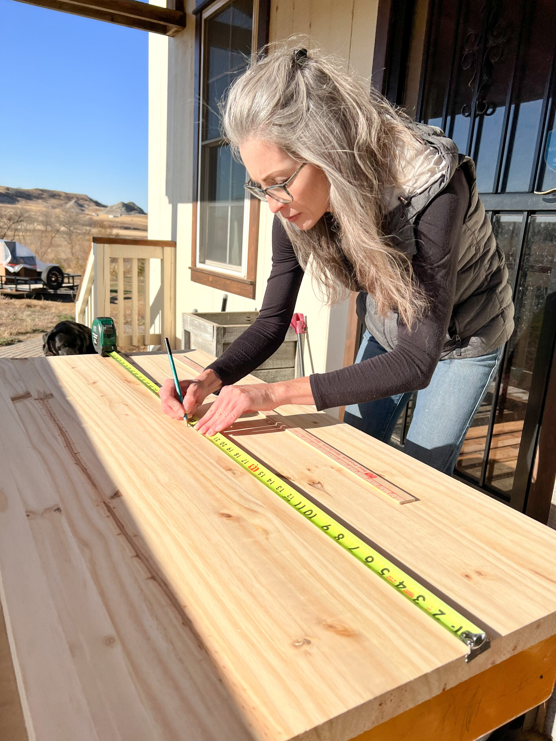 Stephanie Ray measures the piece of wood for the new desk top